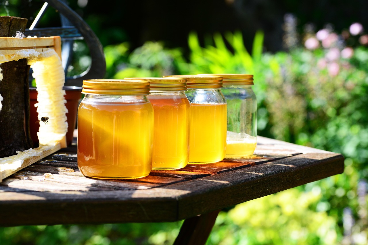Bringing food into Canada for personal use: four jars of honey on a wooden garden table in afternoon sun