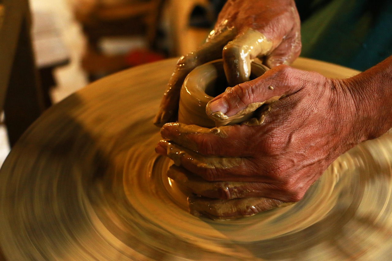 Canada eTA occupation for retired, self-employed or unemployed applicants: a potter's hands shaping clay on a spinning wheel in warm light