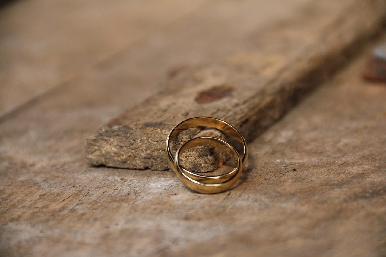 Canada eTA name change after marriage: two gold wedding bands resting on weathered wood in warm light