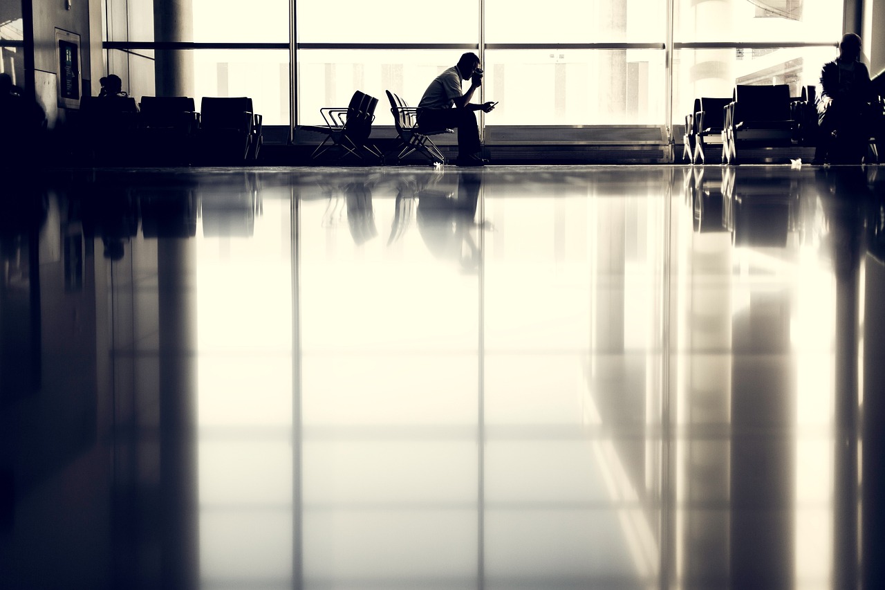 eTA not found at airline check-in: a traveller checking a phone in silhouette by an airport terminal window
