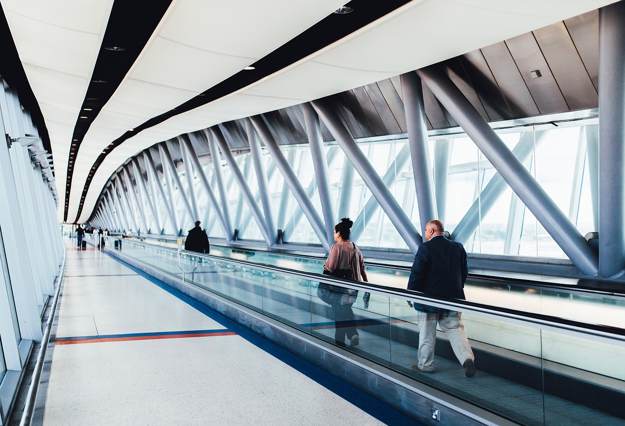 Connecting flight through Canada: travellers on a moving walkway in a long glass terminal corridor