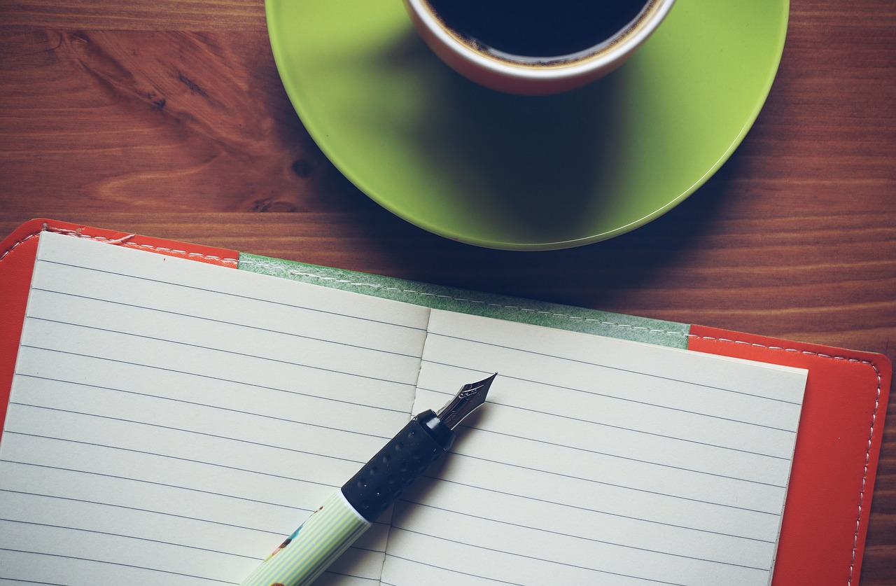 Canada eTA checklist before departure: an open ruled notebook with a fountain pen and a cup of black coffee on a wooden table