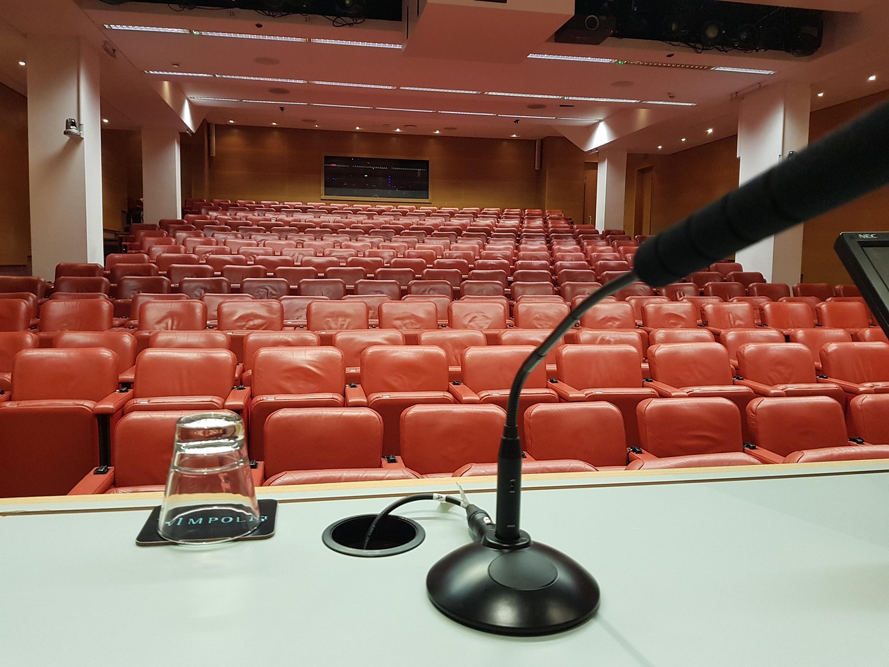 Canada eTA for a conference, trade fair or exhibition: an empty auditorium of red seats with a microphone in the foreground
