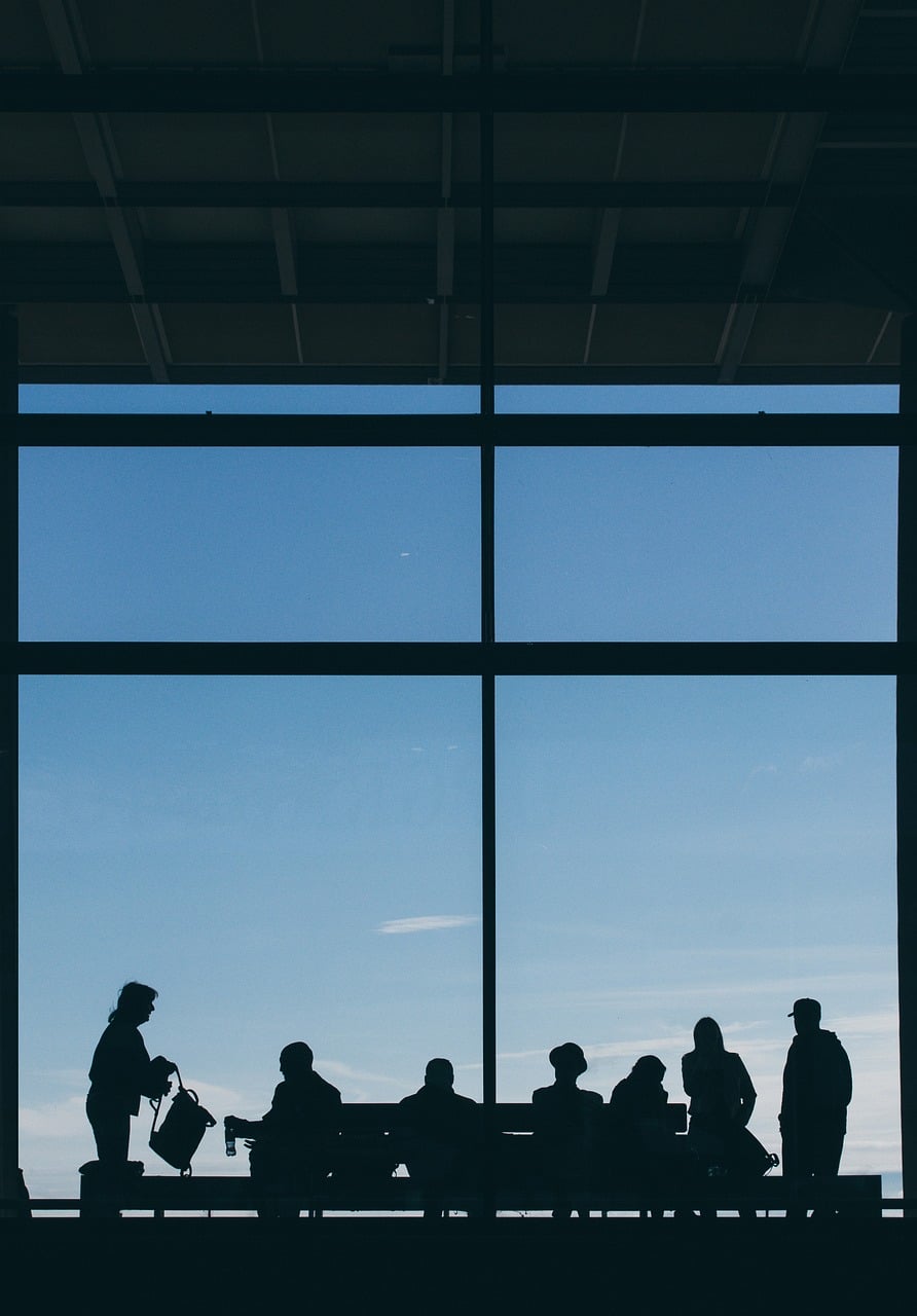 Refugee travel document and Canada eTA: travellers waiting by a tall airport window against a blue sky