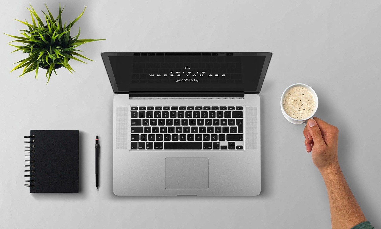 Canada eTA Form Language: English, French and Help in Other Languages: laptop, notebook and cup of coffee on a light desk seen from above