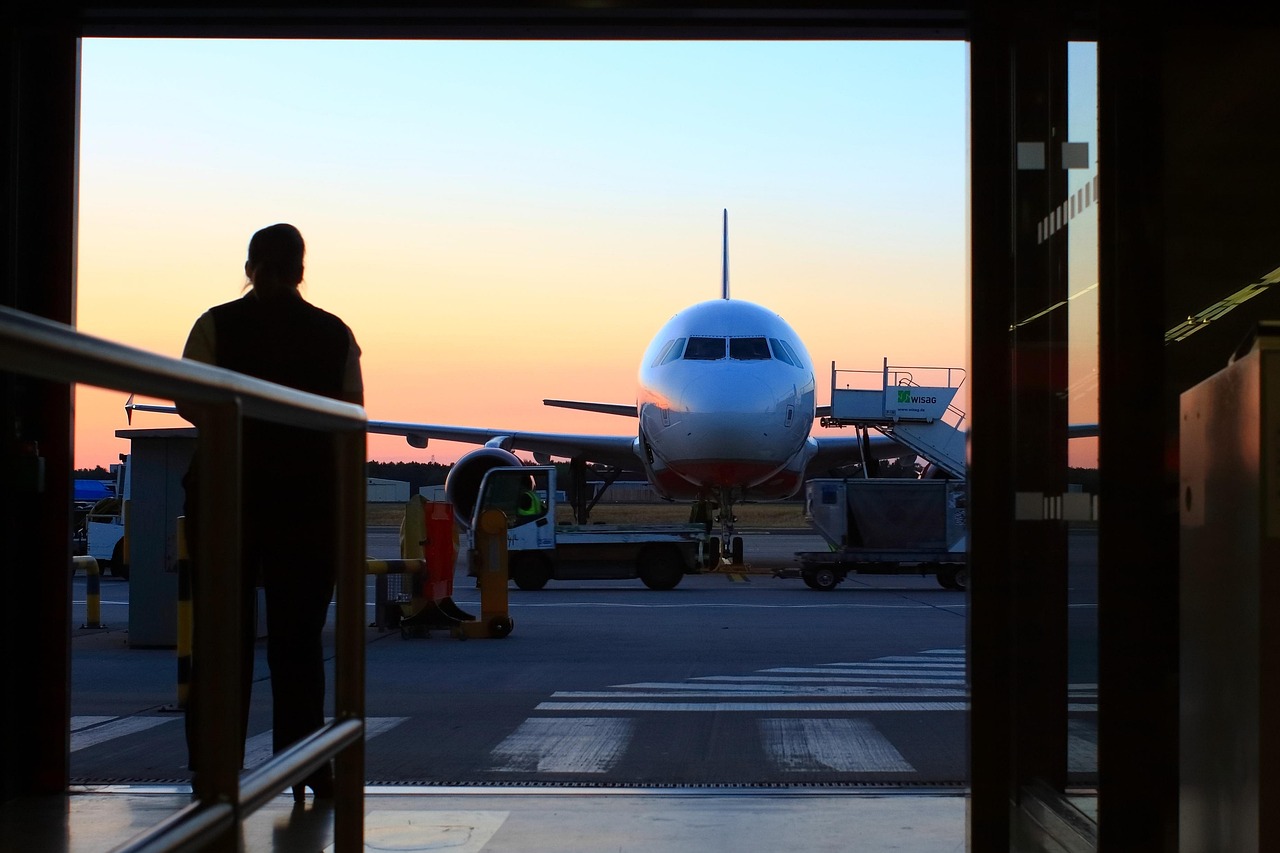 Layover in Canada on an eTA: a traveller silhouetted in an airport doorway watching a plane at dusk