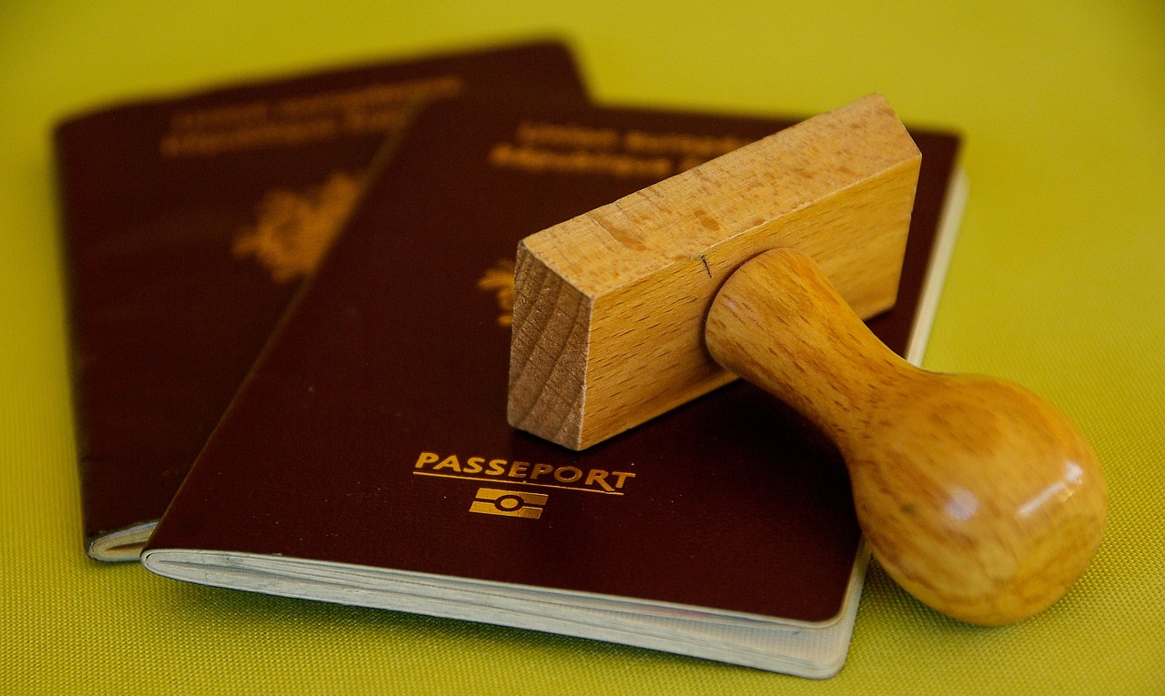 Passport expiring soon and a Canada eTA: two burgundy passports with a wooden rubber stamp on a green surface