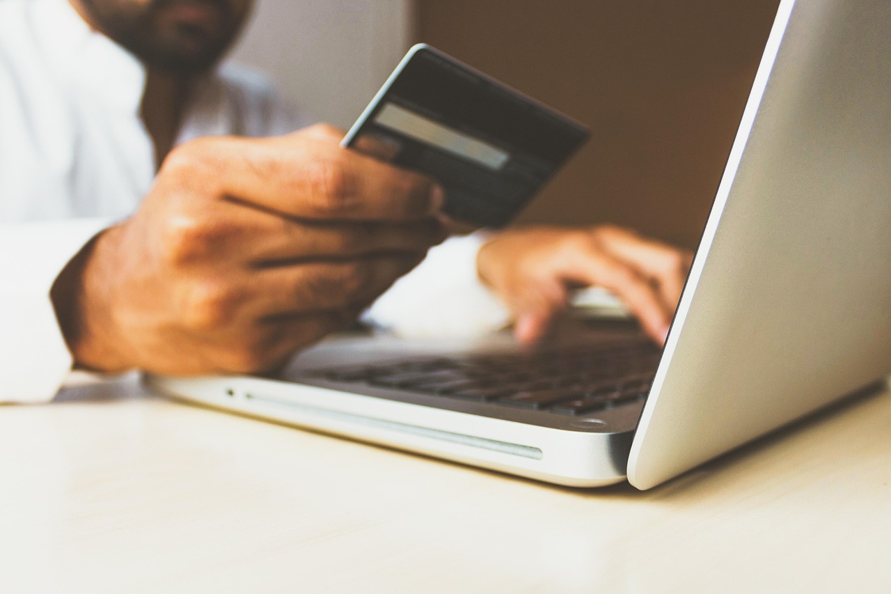 Canada eTA Payment: Accepted Cards, Declined Payments and the 7 CAD Fee: hand holding a bank card above a laptop keyboard